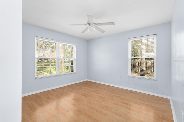 empty room featuring light wood-style floors, baseboards, and a wealth of natural light