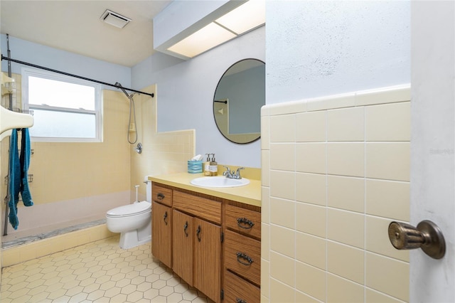 bathroom with visible vents, a tile shower, vanity, and toilet