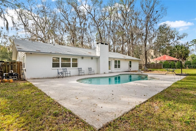 back of property featuring fence, a yard, a fenced in pool, a chimney, and a patio area