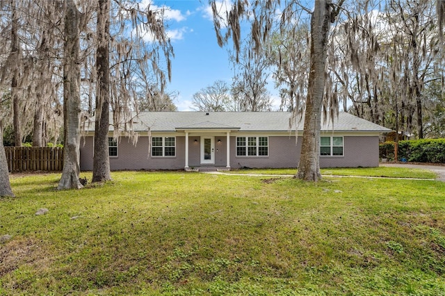 single story home featuring brick siding, fence, and a front yard