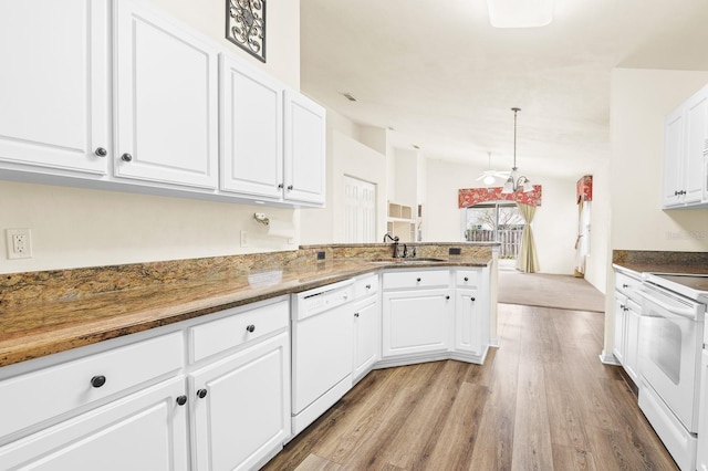 kitchen with a peninsula, white appliances, a sink, wood finished floors, and white cabinetry