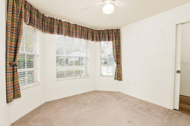 carpeted empty room featuring a ceiling fan and a wealth of natural light