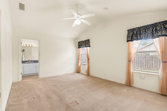 unfurnished bedroom with visible vents, light colored carpet, ensuite bathroom, vaulted ceiling, and a sink