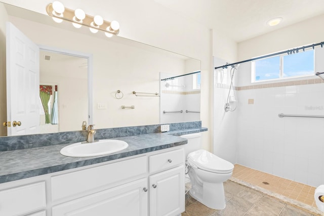 full bath featuring visible vents, tiled shower, vanity, and toilet