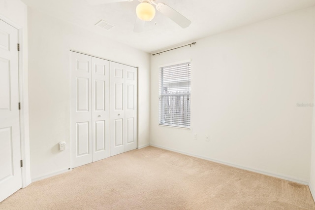 unfurnished bedroom featuring carpet floors, a closet, visible vents, ceiling fan, and baseboards