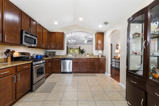 kitchen featuring visible vents, lofted ceiling, light tile patterned flooring, arched walkways, and appliances with stainless steel finishes