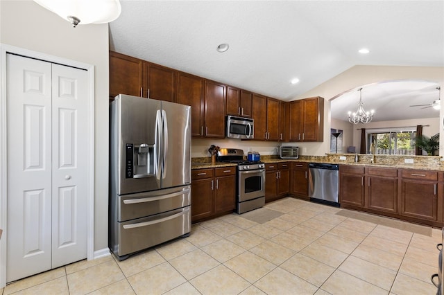 kitchen with light tile patterned floors, arched walkways, a sink, vaulted ceiling, and appliances with stainless steel finishes