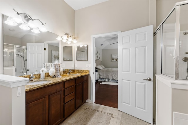 ensuite bathroom with a sink, a shower with door, connected bathroom, tile patterned flooring, and double vanity