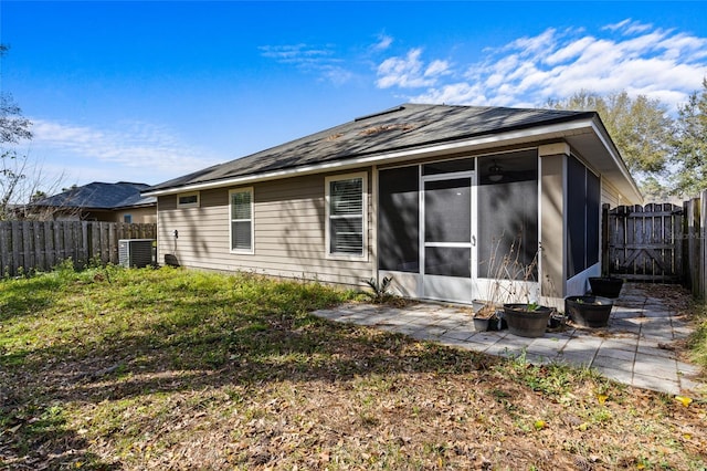 rear view of house featuring a patio, central AC, a fenced backyard, and a sunroom