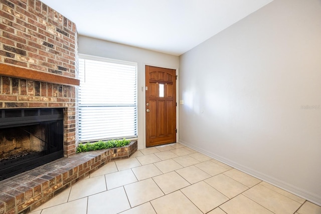 foyer entrance with a brick fireplace, baseboards, and light tile patterned floors