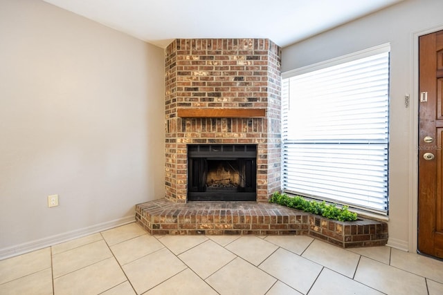 unfurnished living room featuring baseboards, a brick fireplace, and tile patterned floors