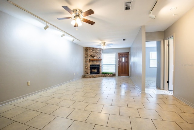 unfurnished living room featuring a fireplace, light tile patterned floors, visible vents, a ceiling fan, and track lighting