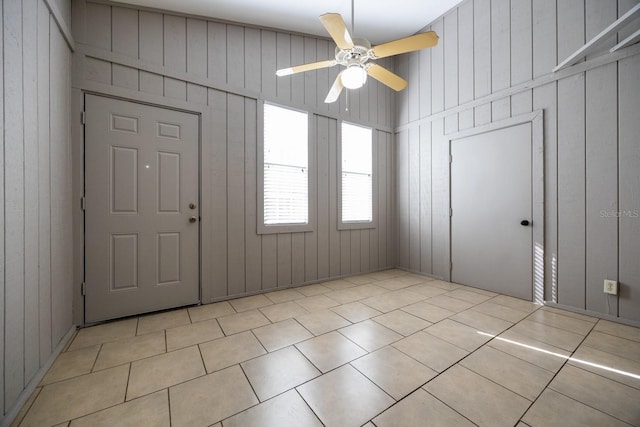 unfurnished room featuring ceiling fan, wood walls, and tile patterned floors