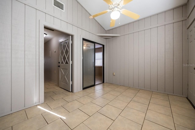 empty room featuring lofted ceiling, visible vents, a ceiling fan, and light tile patterned flooring