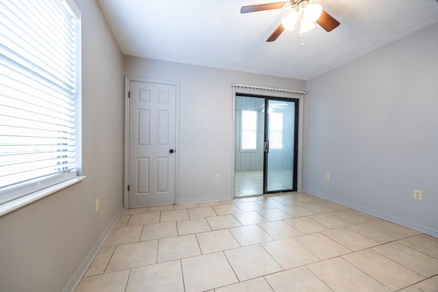 empty room with light tile patterned floors, baseboards, and a ceiling fan