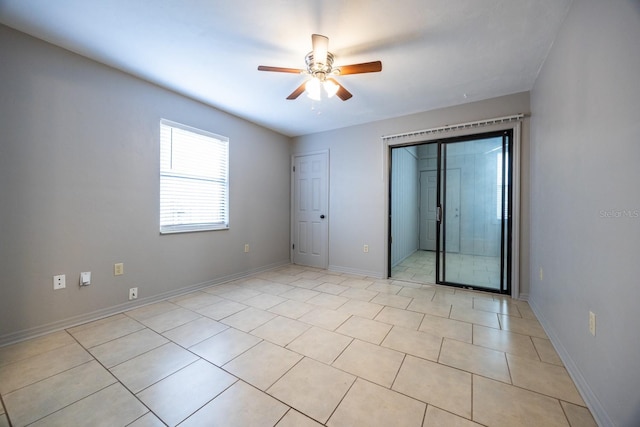 unfurnished room with ceiling fan, light tile patterned floors, and baseboards