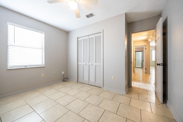 unfurnished bedroom featuring a closet, light tile patterned flooring, visible vents, and baseboards