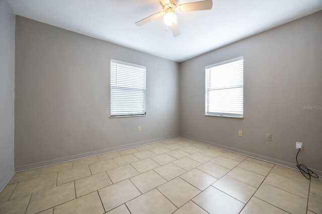 spare room featuring ceiling fan, baseboards, and light tile patterned floors