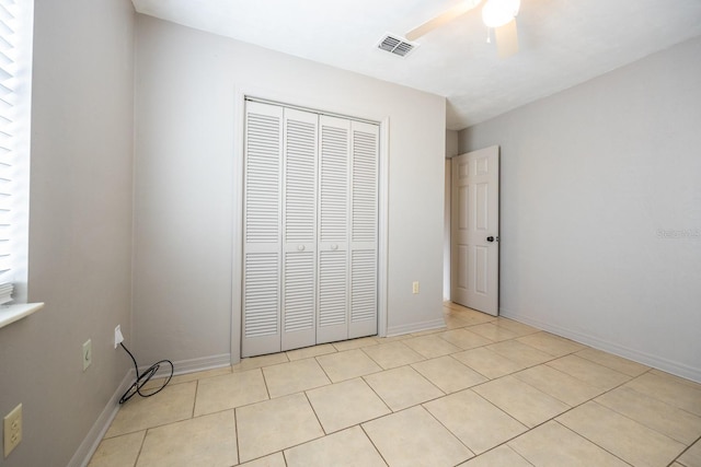 unfurnished bedroom with light tile patterned floors, a closet, visible vents, ceiling fan, and baseboards