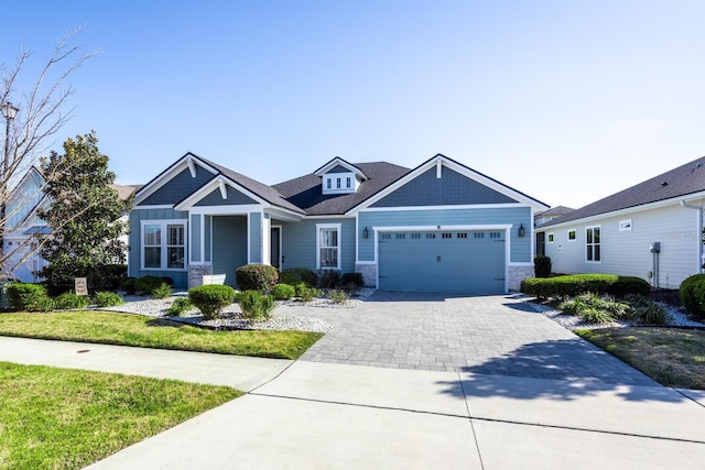 craftsman-style house featuring decorative driveway, a garage, and stone siding