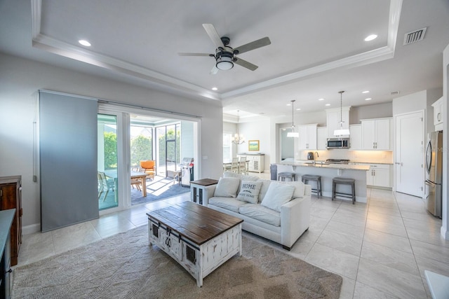 living area featuring a tray ceiling, recessed lighting, and visible vents