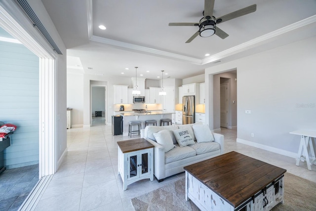 living room featuring recessed lighting, a tray ceiling, baseboards, and ornamental molding