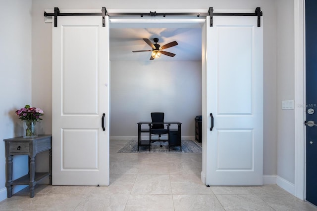 office area with ceiling fan, baseboards, and a barn door