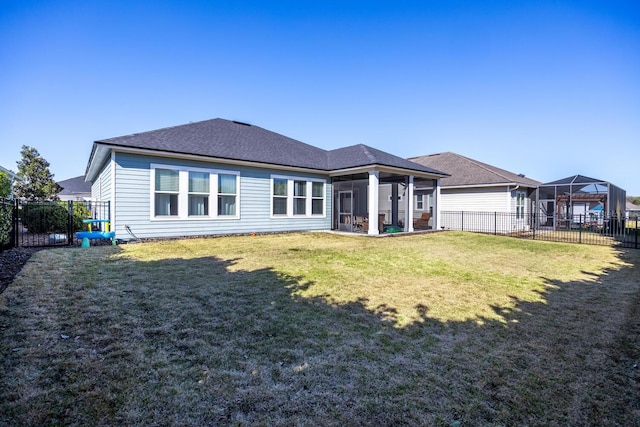 back of property featuring a lawn, roof with shingles, a fenced backyard, and a sunroom