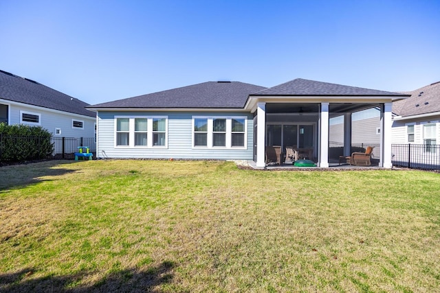 rear view of house with a yard, a shingled roof, a fenced backyard, and a sunroom