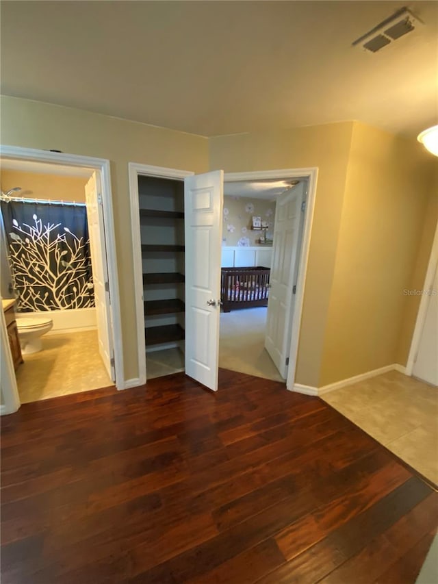 unfurnished bedroom featuring wood finished floors, visible vents, and baseboards