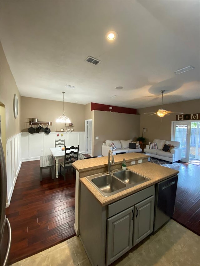 kitchen with visible vents, an island with sink, a sink, dishwasher, and open floor plan