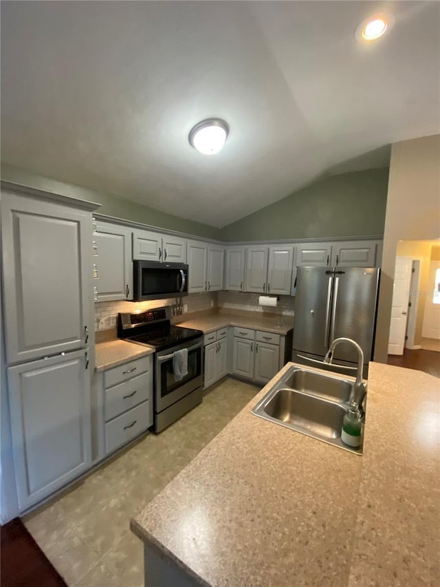 kitchen with light countertops, lofted ceiling, decorative backsplash, stainless steel appliances, and a sink