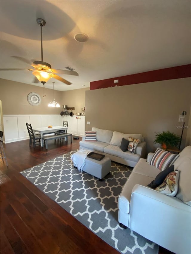 living area with a decorative wall, a ceiling fan, and wood finished floors