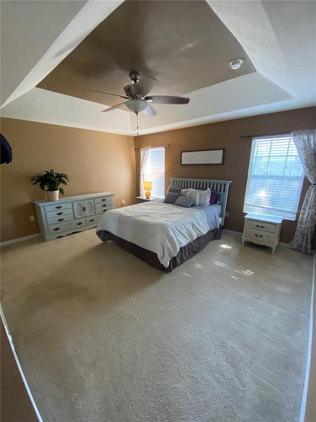 unfurnished bedroom featuring multiple windows, carpet, and a tray ceiling