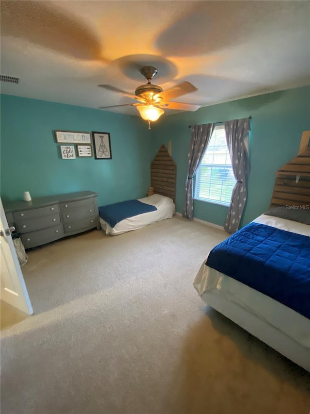 bedroom featuring visible vents, a textured ceiling, a ceiling fan, and carpet