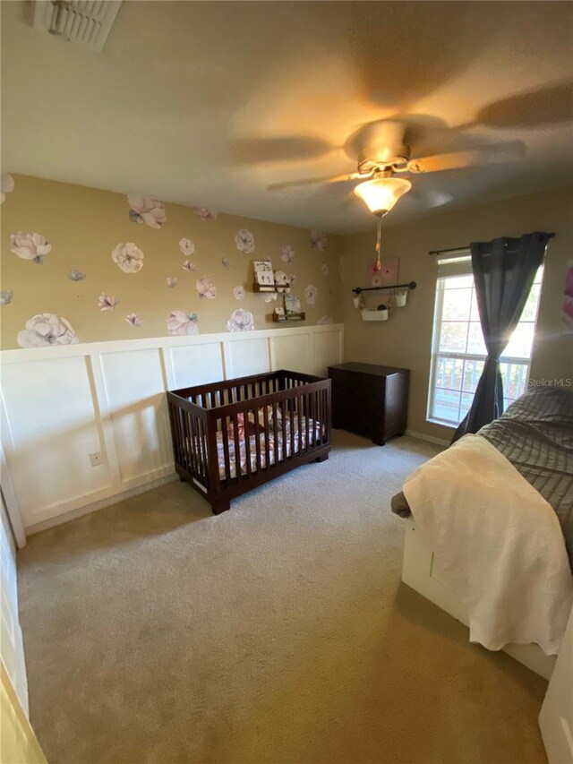 bedroom with visible vents, a wainscoted wall, a ceiling fan, carpet flooring, and wallpapered walls