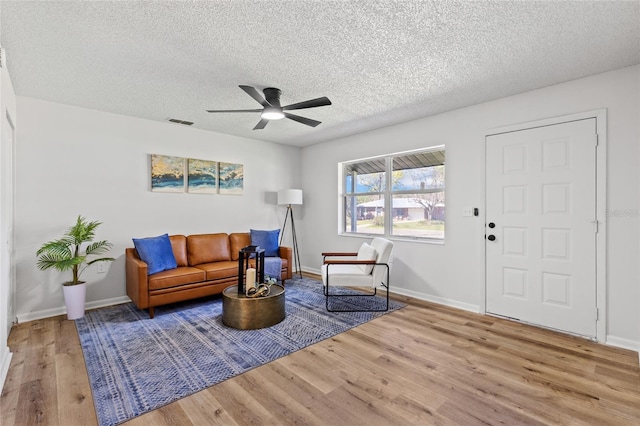 interior space featuring visible vents, a ceiling fan, a textured ceiling, wood finished floors, and baseboards