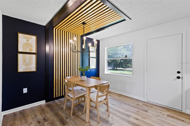 dining area with a textured ceiling, wood finished floors, and baseboards