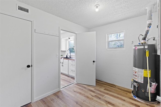 interior space with water heater, a sink, and visible vents