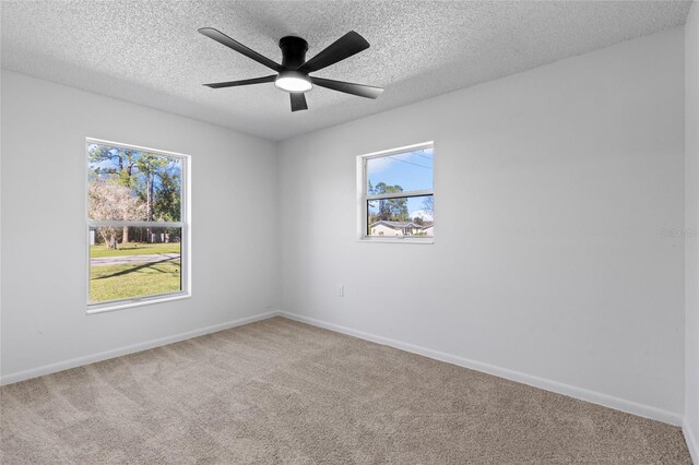 carpeted empty room with ceiling fan, baseboards, and a textured ceiling