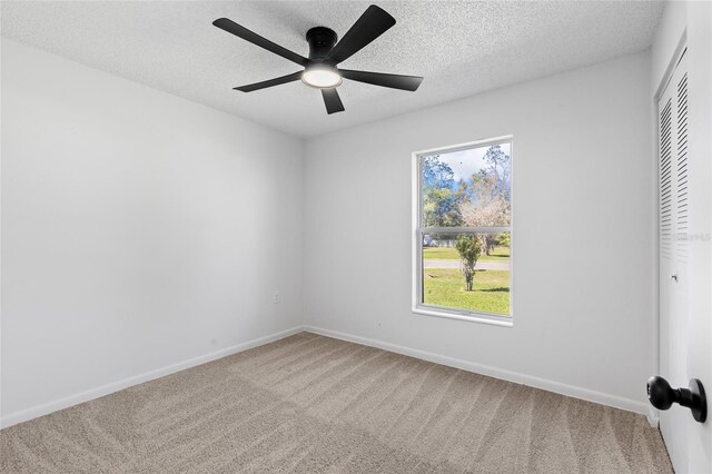 carpeted empty room featuring ceiling fan, baseboards, and a textured ceiling