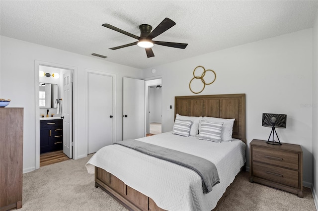 bedroom featuring visible vents, light colored carpet, ceiling fan, a textured ceiling, and a sink