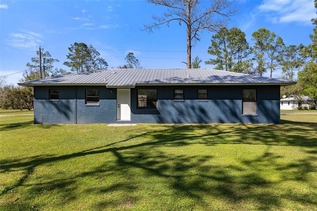 rear view of property with a yard, metal roof, and stucco siding