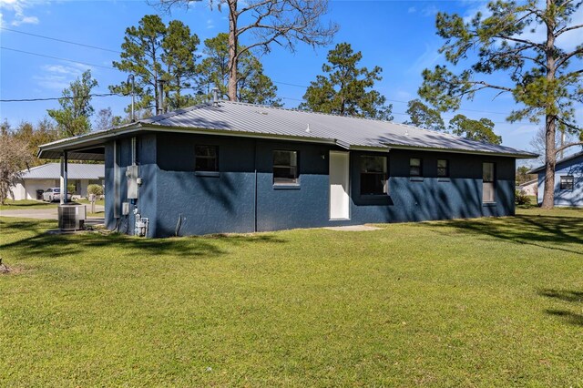 back of property featuring a yard, metal roof, cooling unit, and stucco siding