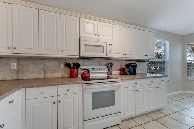 kitchen featuring white appliances, light tile patterned floors, baseboards, white cabinetry, and backsplash