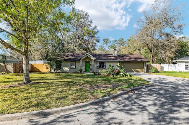 single story home with a front yard, fence, driveway, an attached garage, and a chimney