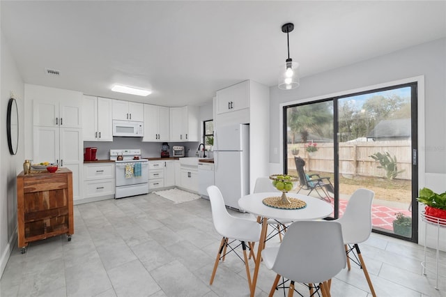 interior space with visible vents, a healthy amount of sunlight, white appliances, and white cabinets