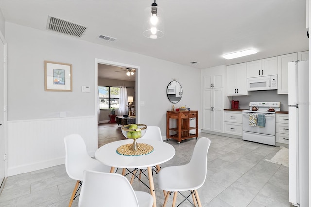 dining space with visible vents, a wainscoted wall, and a ceiling fan