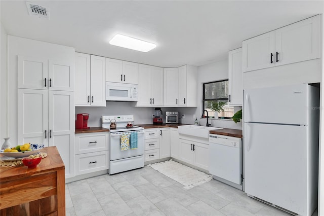 kitchen featuring a sink, visible vents, white appliances, and white cabinetry