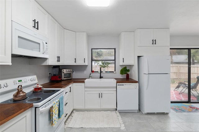 kitchen with a toaster, butcher block counters, white cabinets, white appliances, and a sink